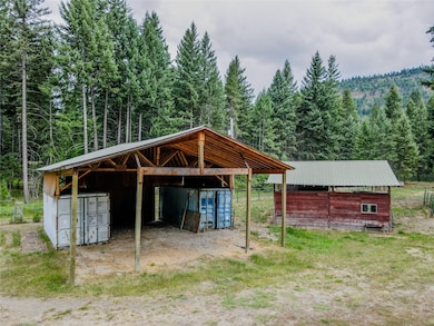 View of outdoor structure with a detached carport, a view of trees, and an exterior structure