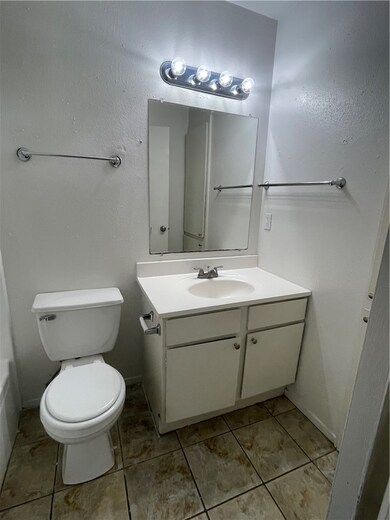 Half bath with toilet, tile patterned floors, base