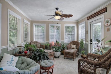 Sunroom featuring a textured ceiling, ornamental molding, and tile patterned flooring