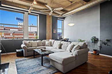 Living room with a high ceiling, ceiling fan, baseboards, and wood finished floors