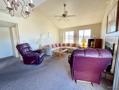 Carpeted living room with vaulted ceiling, a firep