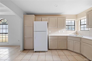 Kitchen with tasteful backsplash, sink, light tile patterned flooring, and white fridge