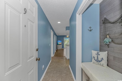 Hallway featuring light tile patterned floors, a textured ceiling, and recessed lighting