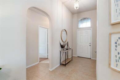 Foyer with baseboards, arched walkways, light tile