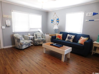 Living area with ornamental molding and dark wood-style floors
