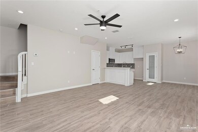 Unfurnished living room with light wood-style floors, recessed lighting, baseboards, and ceiling fan with notable chandelier