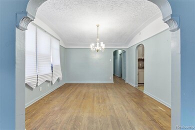 Spare room featuring arched walkways, a textured ceiling, light wood-style floors, a chandelier, and lofted ceiling