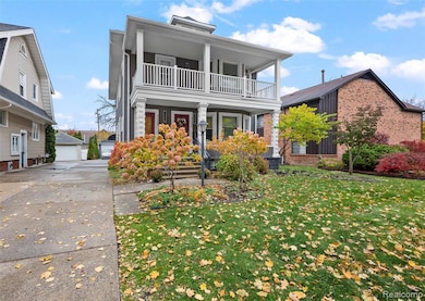 View of front facade featuring a porch, a front yard, a garage, and an outbuilding