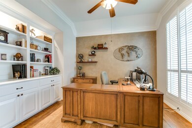 Beautiful study with plantation shutters, wood floors, custom built-ins, and double crown molding.
