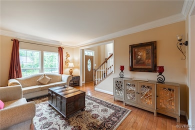Living room with crown molding, stairs, hardwood /