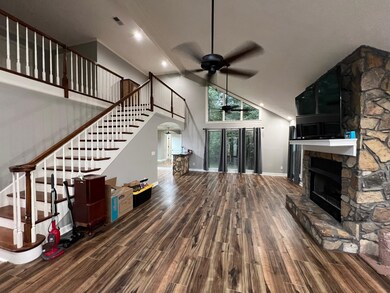 Living room with ceiling fan, a stone fireplace, h