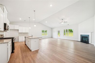 Kitchen featuring stainless steel appliances, white cabinets, light wood-style flooring, pendant lighting, and light stone countertops