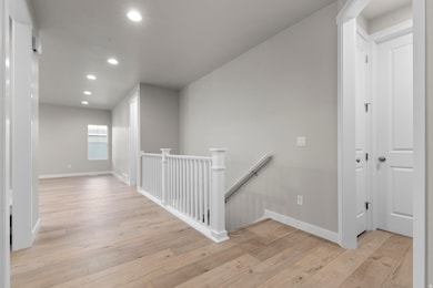 Hall with an upstairs landing, recessed lighting, and light wood-style floors