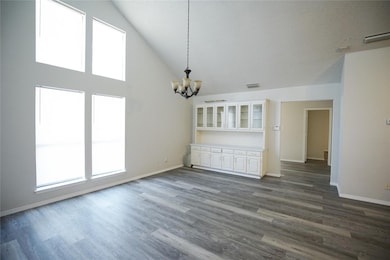 Unfurnished dining area with high vaulted ceiling, dark wood finished floors, and a chandelier