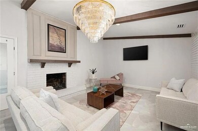 Living area featuring light marble finish flooring, beamed ceiling, a brick fireplace, and a chandelier