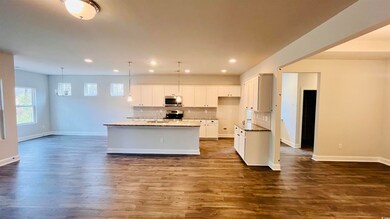 Kitchen with white cabinetry, sink, hanging light 