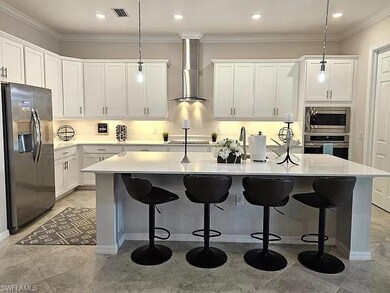 Kitchen with stainless steel appliances, wall chimney range hood, white cabinetry, light countertops, and recessed lighting