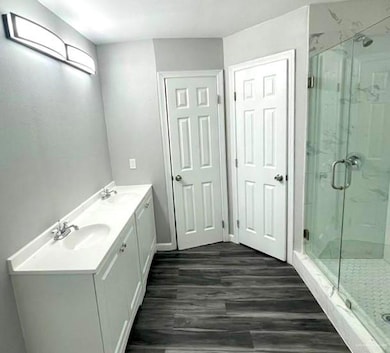 Bathroom with wood-type flooring, vanity, and walk in shower