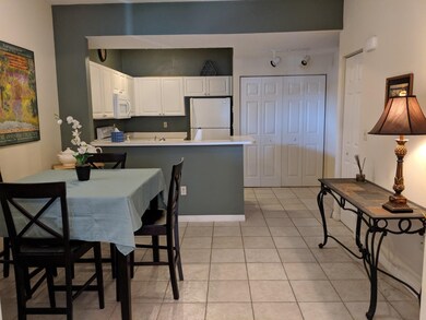 Kitchen featuring freestanding refrigerator, white cabinetry, light tile patterned floors, a peninsula, and light countertops