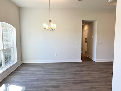 Unfurnished room with dark wood finished floors and a chandelier