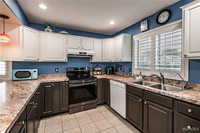 Kitchen featuring under cabinet range hood, a sink