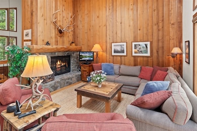 Carpeted living area featuring a stone fireplace a
