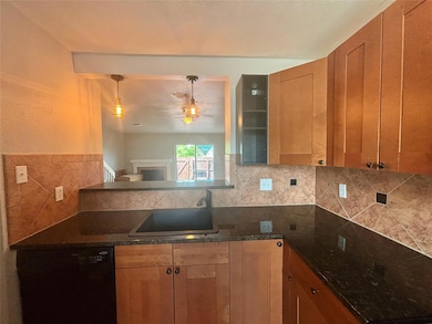 Kitchen with black dishwasher, backsplash, hangin
