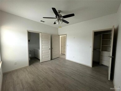 Unfurnished bedroom featuring a spacious closet, wood finished floors, visible vents, and baseboards