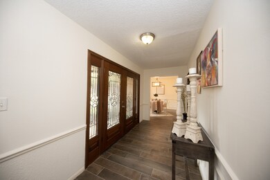 Enter the double glass door into the foyer with wood look tile. Privacy wall complete with chair molding.