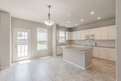 Kitchen featuring backsplash, decorative light fixtures, light tile patterned flooring, light stone counters, and a kitchen island