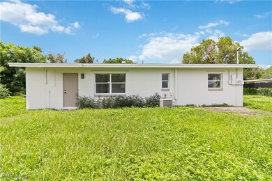 Rear view of house featuring a lawn and central AC