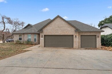 View of front of house featuring roof with shingles, an attached garage, brick siding, and driveway