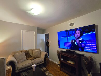 Living room with visible vents, baseboards, and wo