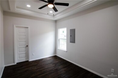 Unfurnished room featuring a raised ceiling, ceiling fan, and dark wood-type flooring