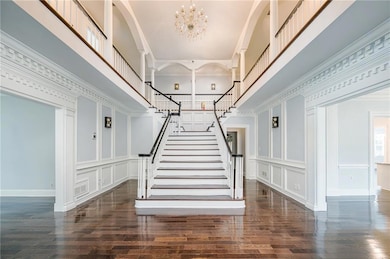 Stairway with a chandelier, a towering ceiling, wood finished floors, and crown molding