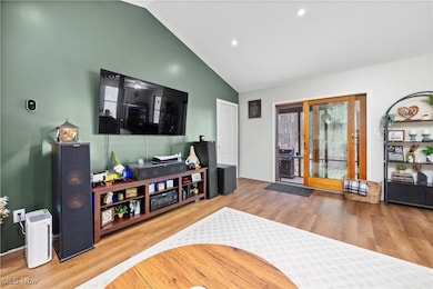 Living area with high vaulted ceiling, wood finished floors, and recessed lighting