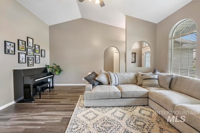 Living room with vaulted ceiling, dark wood-style floors, ceiling fan, and arched walkways