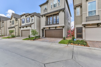 Modern multi-story townhouse with a brown garage door and balcony. The exterior is well-maintained with a small front garden and paved driveway, situated in a neatly arranged neighborhood.