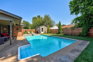 View of pool when uncovered featuring a fenced backyard, a patio area, a storage shed, and a diving board