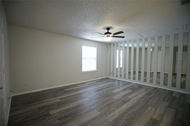 Empty room featuring dark wood-style flooring, a textured ceiling, and a ceiling fan
