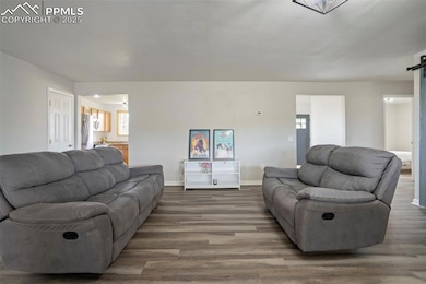 Living room with a barn door, wood finished floors, and baseboards