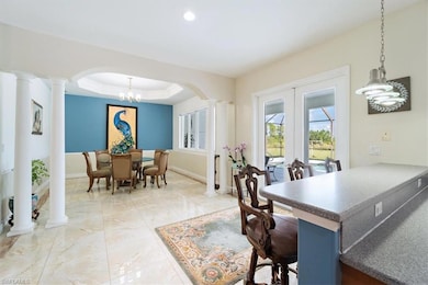 Dining area with ornate columns, light marble finish flooring, arched walkways, baseboards, and recessed lighting