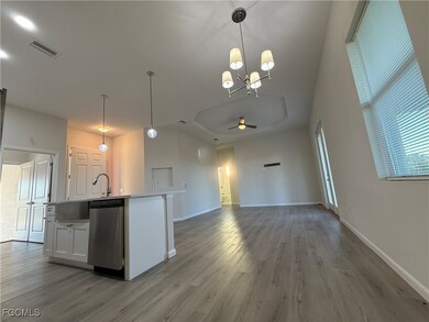 Kitchen featuring hanging light fixtures, white cabinetry, open floor plan, and stainless steel dishwasher