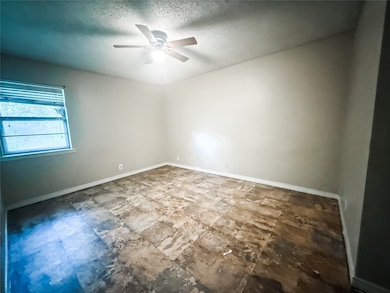 Empty room with a ceiling fan and a textured ceiling