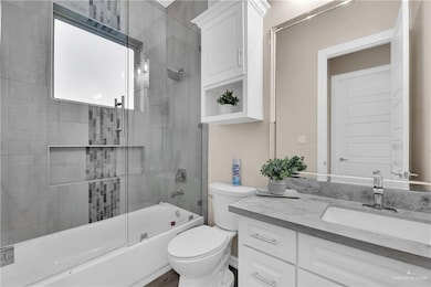Bathroom with toilet, enclosed tub / shower combo, and vanity