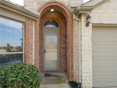 Doorway to property featuring stone siding, a garage, and brick siding