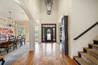 Fabulous wrought iron chandelier lighting leads the way to the wrought iron & wood-stained staircase and don't miss the custom arched wrought iron front door with sidelights & transom above.