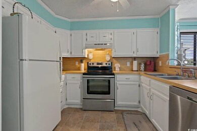 Kitchen with appliances with stainless steel finishes, a sink, under cabinet range hood, light countertops, and white cabinetry