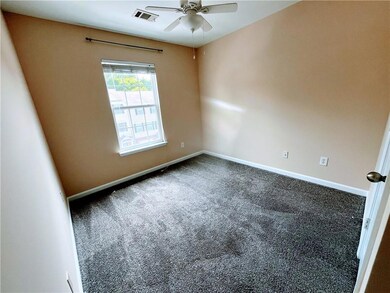 Carpeted spare room with a ceiling fan, baseboards