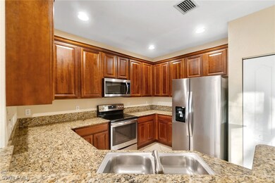 Kitchen featuring stainless steel appliances, light stone countertops, recessed lighting, and brown cabinets